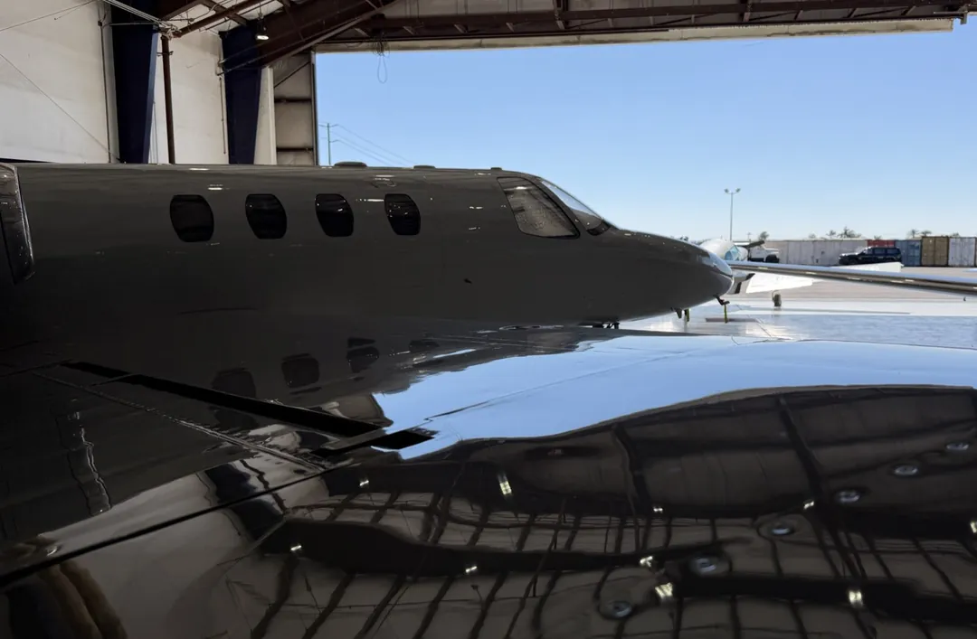 Jet wing polished to a mirror finish, hangar door open behind it