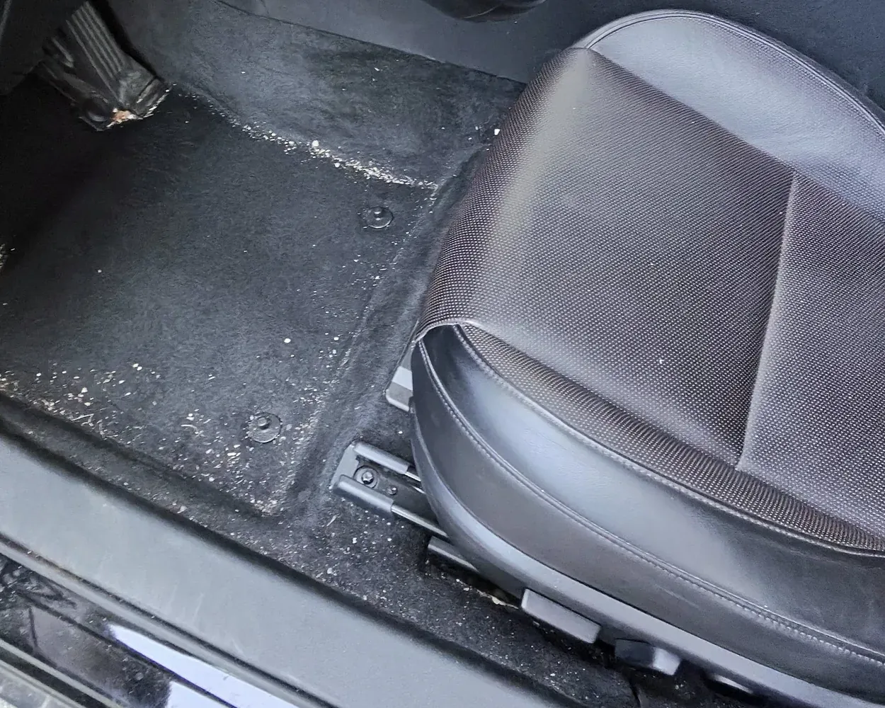 Driver&rsquo;s footwell and seat before the interior detail, carpet covered in debris