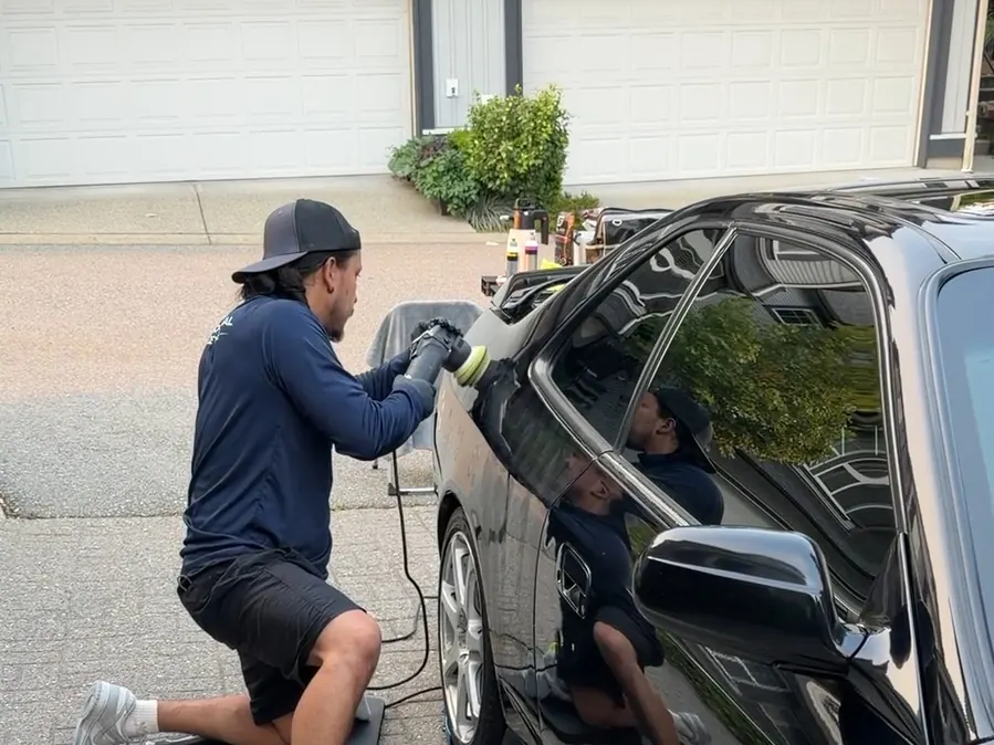 Machine polishing the side of a black car on a driveway