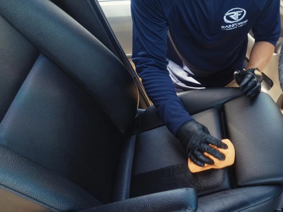 Cleaning a black leather seat by hand