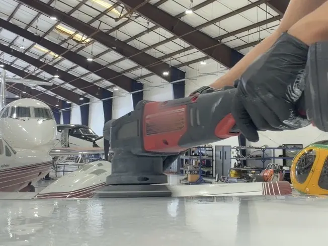 Machine polishing the paint on an aircraft wing inside a hangar
