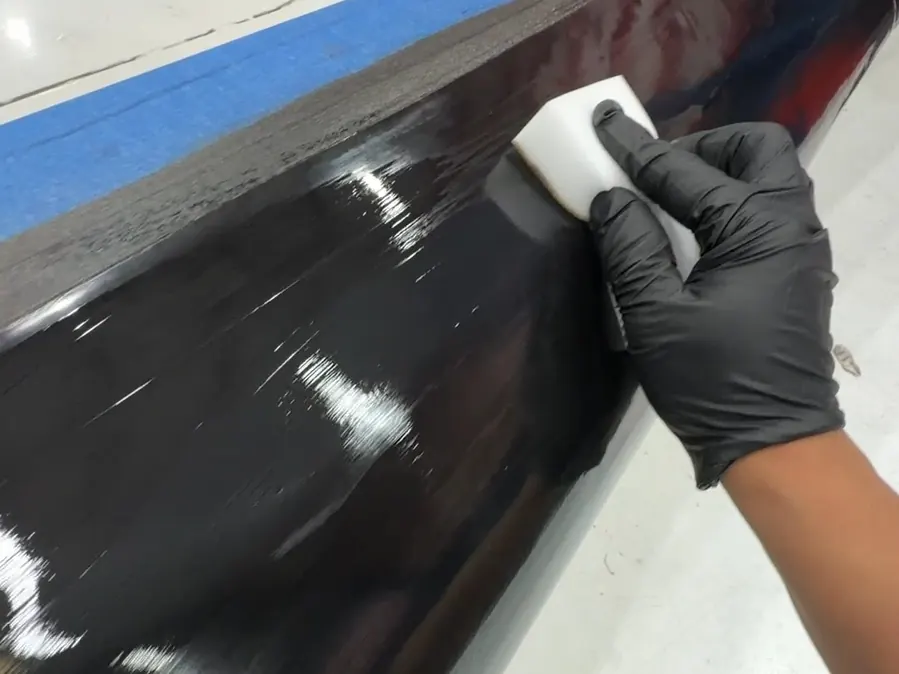 Treating a de-ice boot by hand, the wing masked with tape