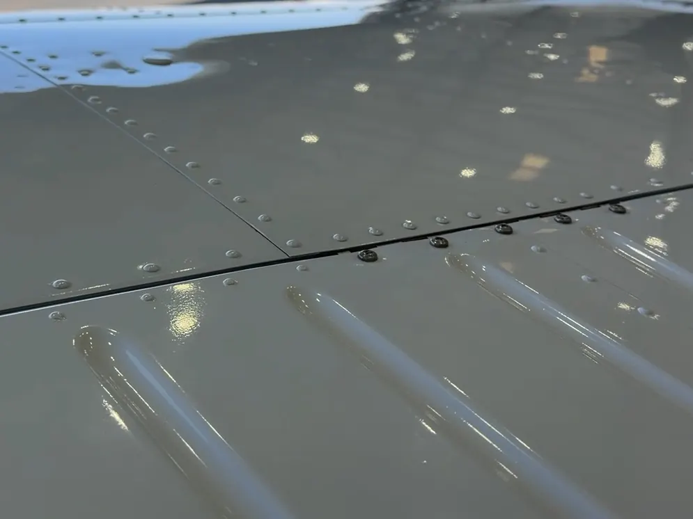 A glossy aircraft wing reflecting the sun on the ramp